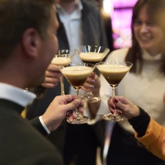 Bild von vier Personen, die mit Cocktails anstoßen.