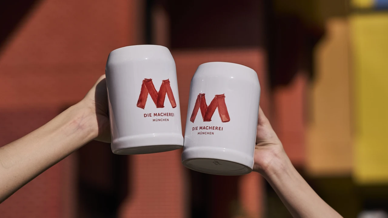 Zwei Bierkrüge vor der Fassade der Macherei München